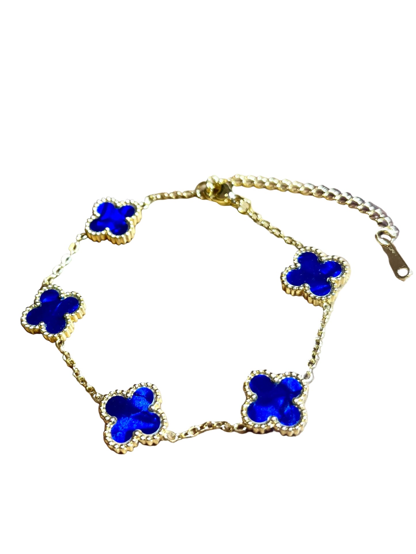 Gold bracelet with blue flower-shaped charms on a white surface