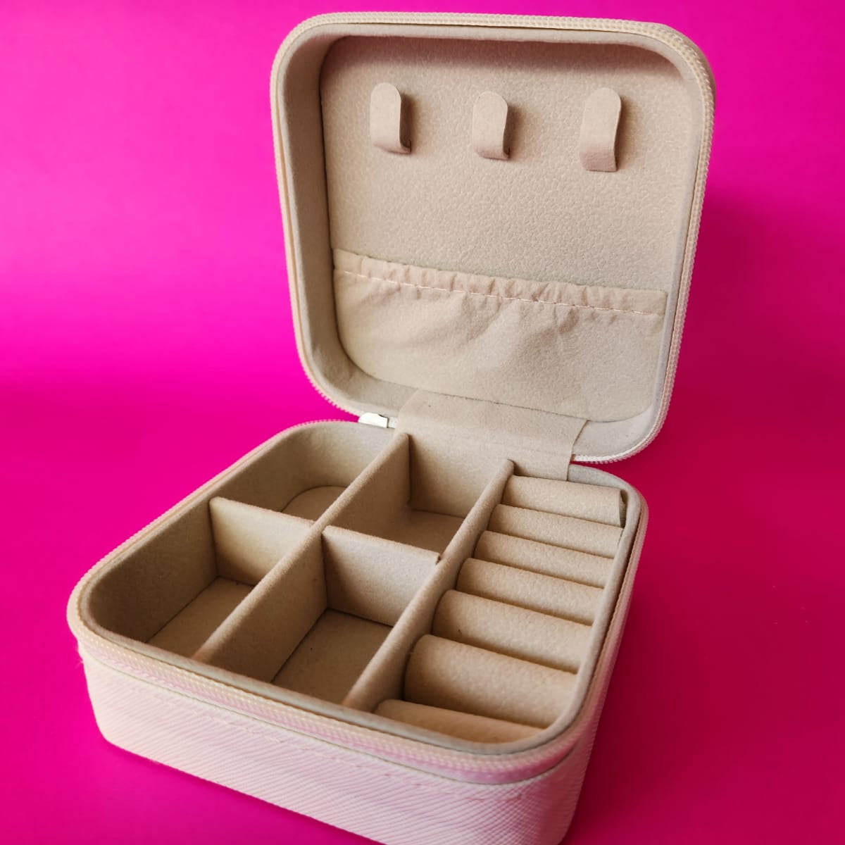 Beige jewelry case with compartments on a pink background