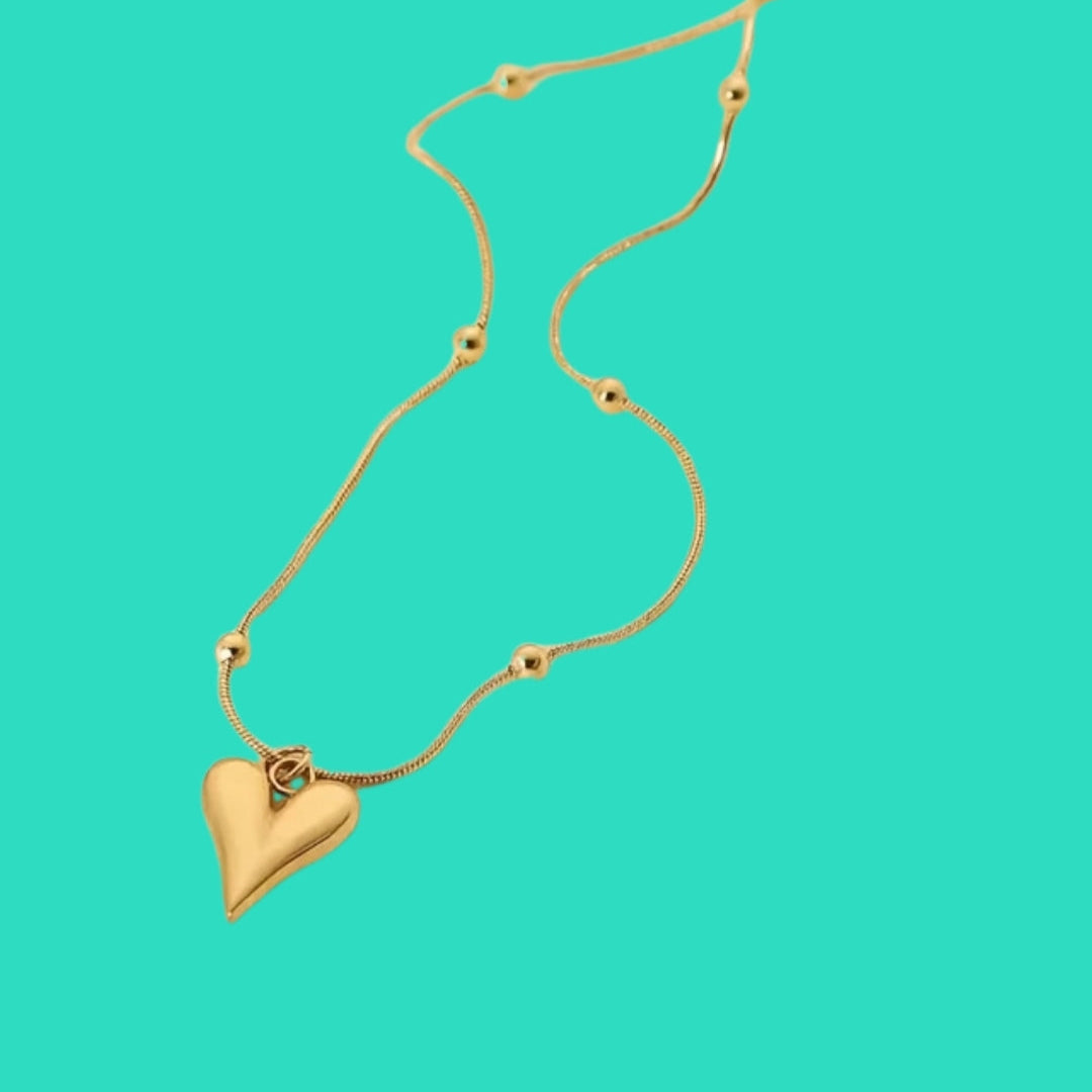 Gold heart-shaped pendant necklace on a turquoise background
