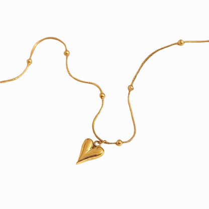 Gold necklace with a heart-shaped pendant on a white background