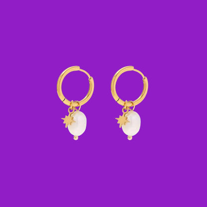 Gold hoop earrings with white stones and star charms on a purple background