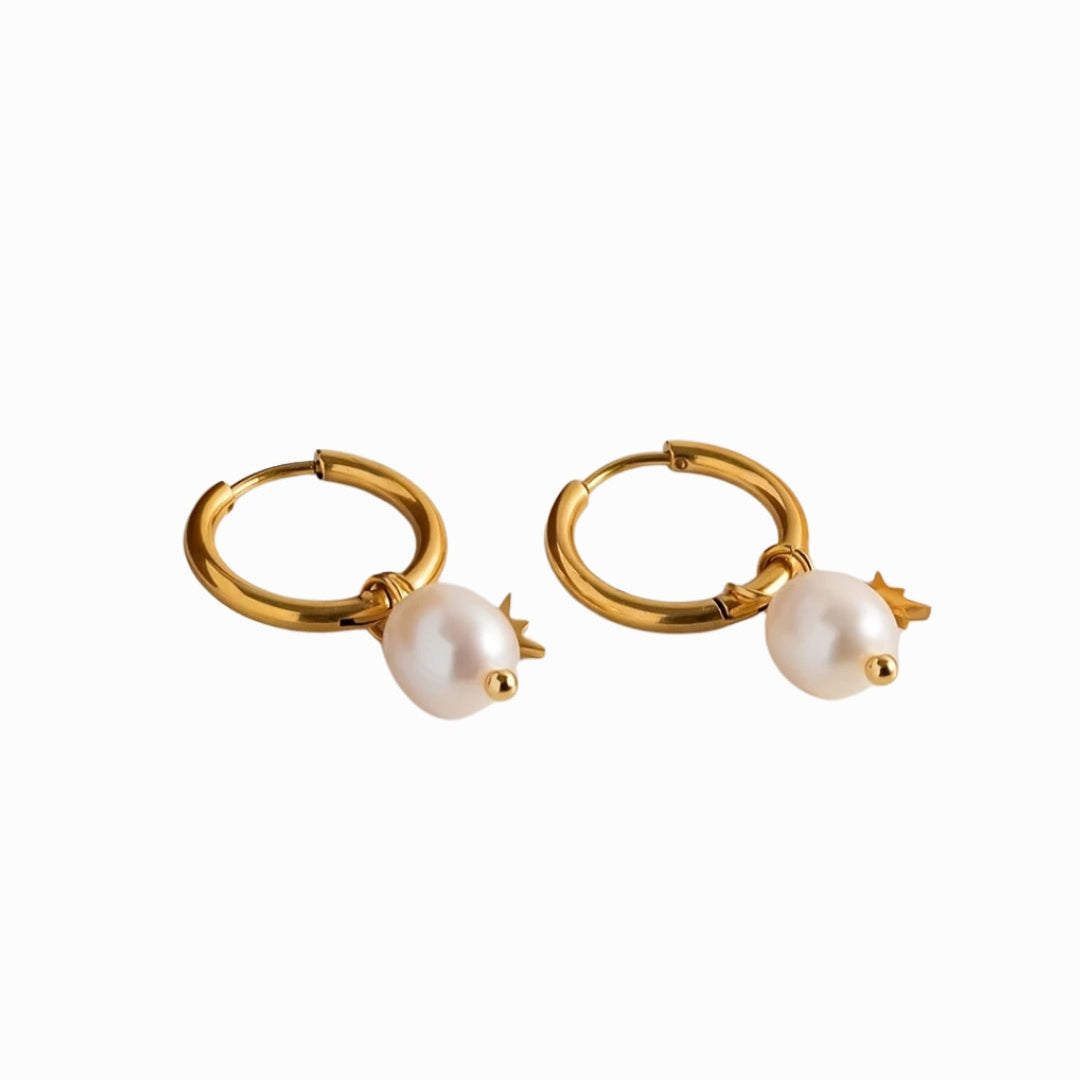 Gold hoop earrings with pearl charms on a white background