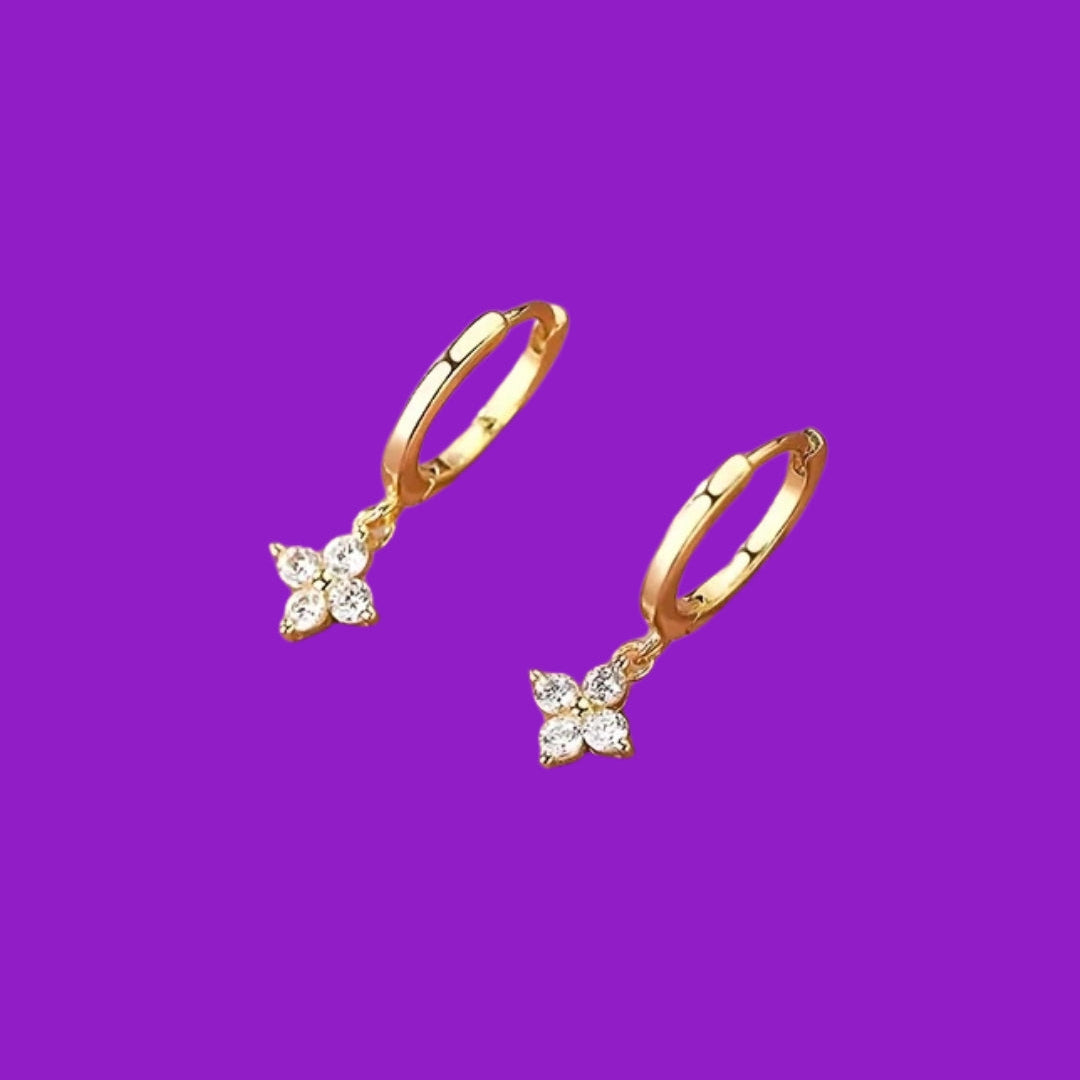 Gold hoop earrings with charms on a purple background