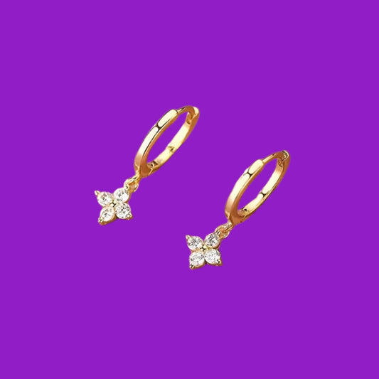 Gold hoop earrings with charms on a purple background